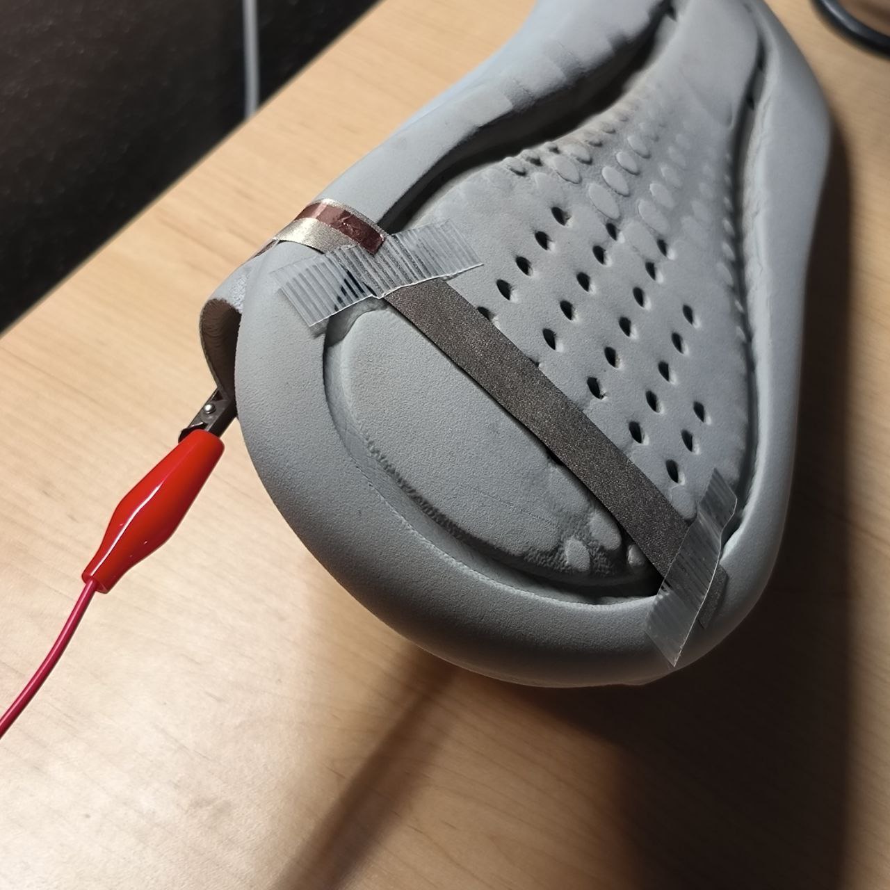 Copper tape is attached to the underside of the slipper and connected with an alligator clip. This transforms the slipper into an interactive input device, acting as a physical interface for the pedal areas defined earlier.